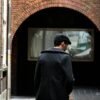 man on narrow pathway between concrete buildings