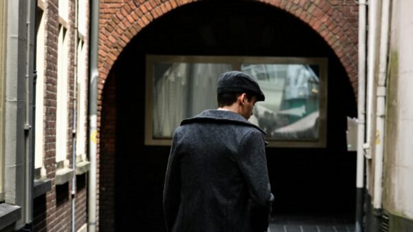 man on narrow pathway between concrete buildings