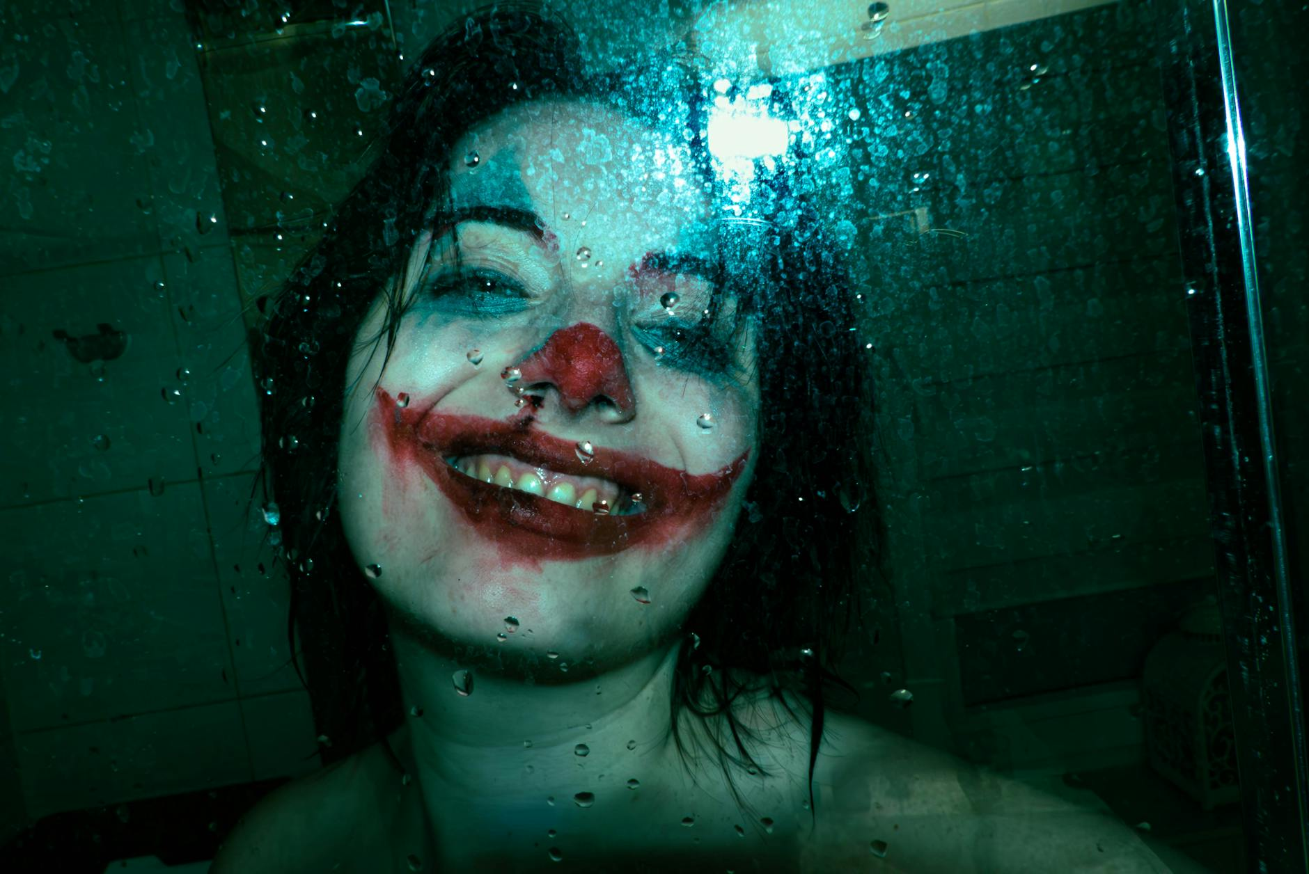 eerie joker smile behind wet glass
