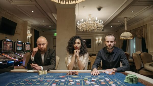 a woman and men sitting at a gaming table with stacks of casino tokens
