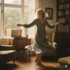 “Joyful midlife woman dancing barefoot in her living room near a record player, sunlight streaming through large windows.”