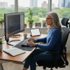 Woman working at a desk on a computer with code on the screen in a bright home office