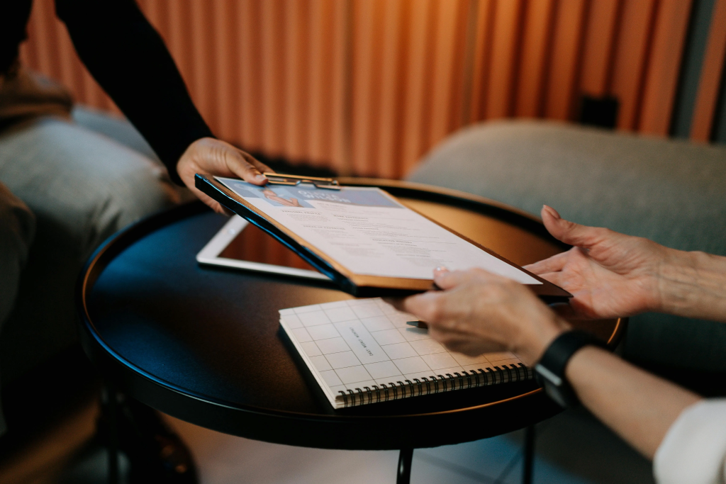 Two people exchanging paperwork during a creative upgrade in your 40s