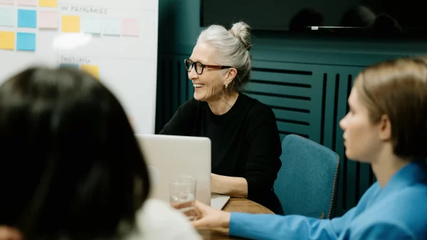 Smiling older woman leading a creative meeting, representing the rise of over-40 creators shaping modern workspaces.