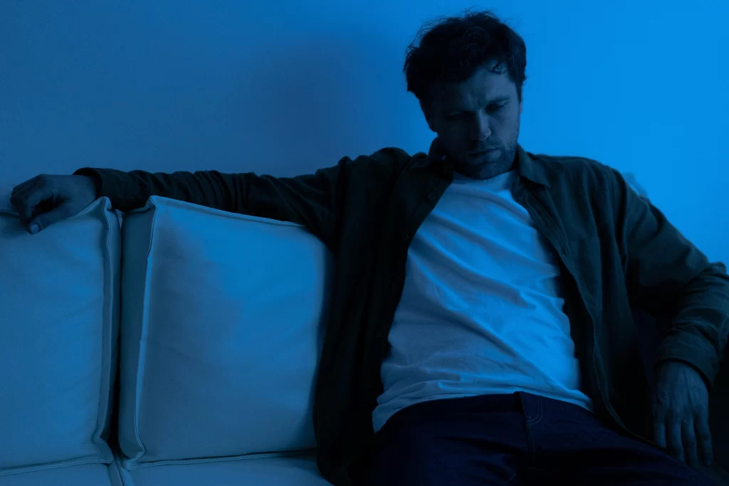 Man sitting alone on a couch under blue light, reflecting on late-life reinvention and the rise of over-40 creators.