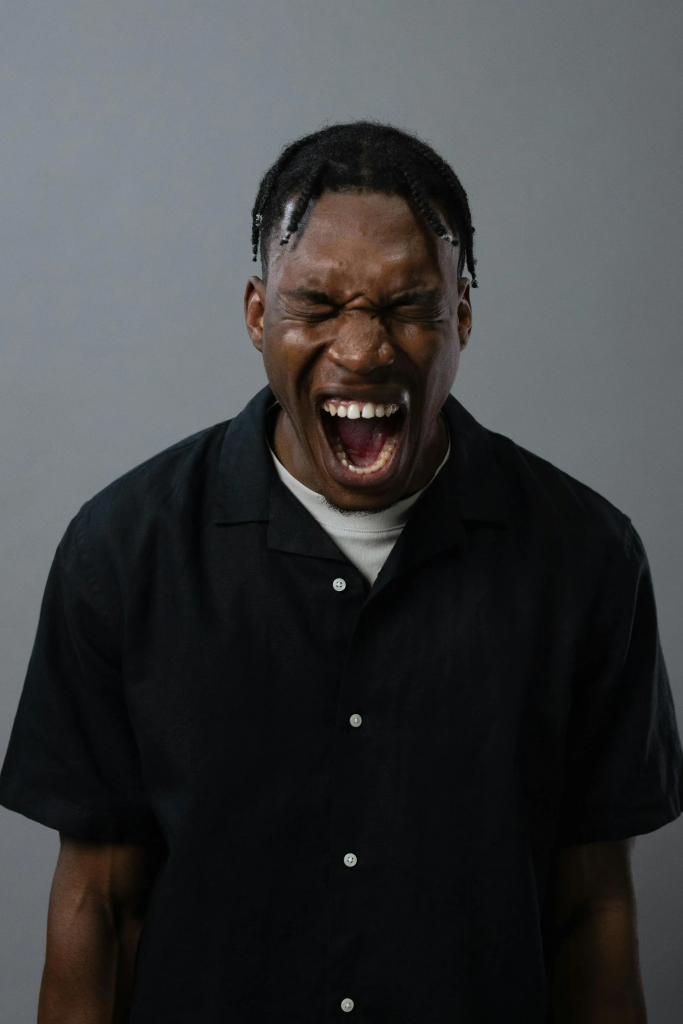 Man screaming with eyes closed in emotional frustration