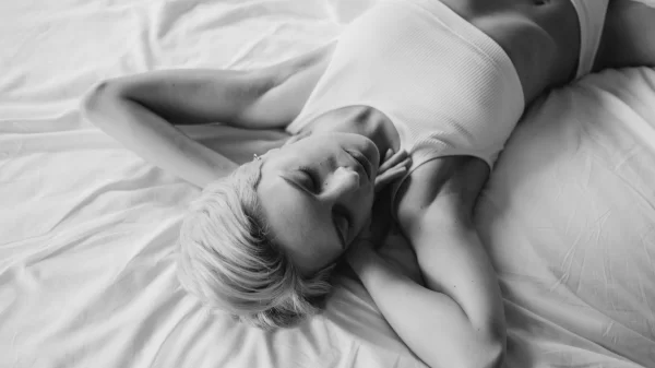 Woman resting on a bed, symbolizing self-connection and the new rules of midlife intimacy.