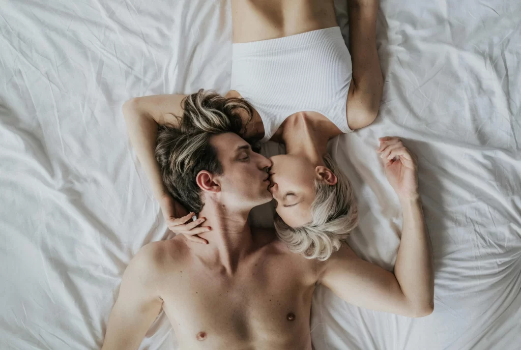 Couple kissing while lying on the bed, capturing emotional and physical connection in the new rules of midlife intimacy.