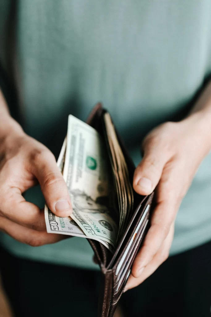 Person counting cash from a wallet, reflecting savings regret and budgeting choices