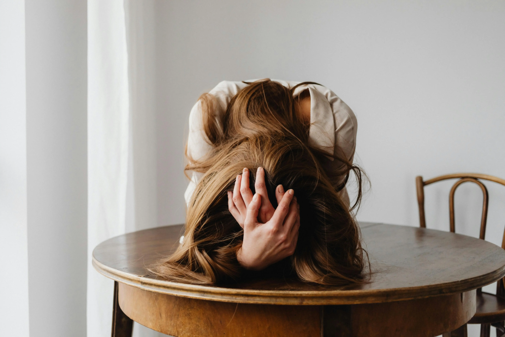 Woman with her head down on a wooden table, expressing emotional overwhelm during a midlife brain reset.