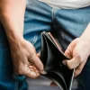 Man opening an empty wallet, representing savings regret and financial stress