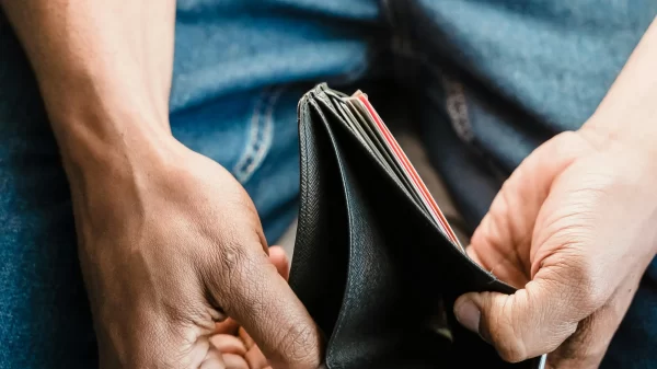 Man opening an empty wallet, representing savings regret and financial stress