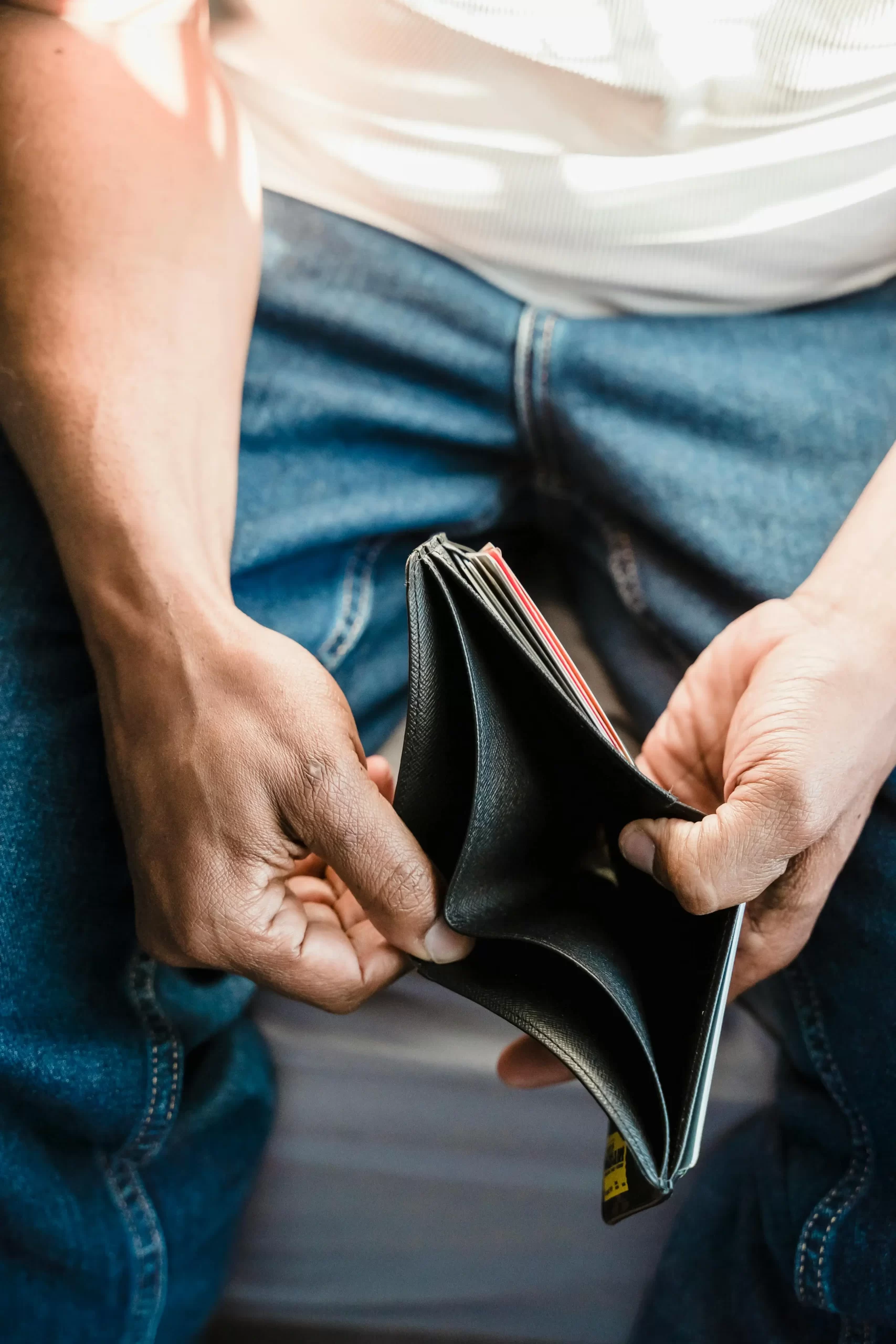 Man opening an empty wallet, representing savings regret and financial stress
