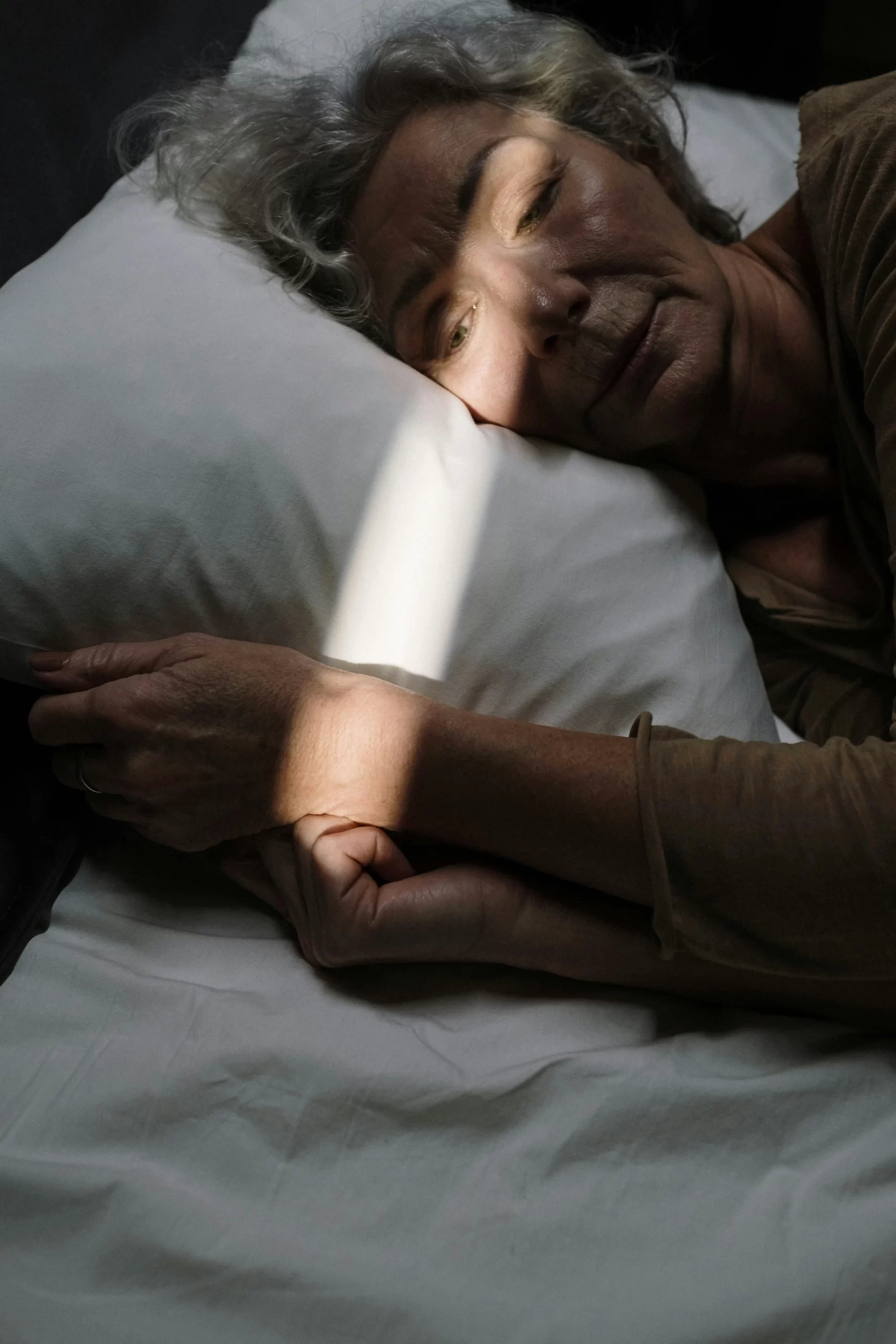 Older woman resting in bed with sunlight on her face, representing how sleep hits different after 45.