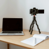 Creative desk setup with a laptop, camera, and notebook — perfect tools for starting the $100 start project.