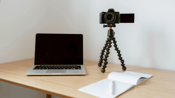 Creative desk setup with a laptop, camera, and notebook — perfect tools for starting the $100 start project.