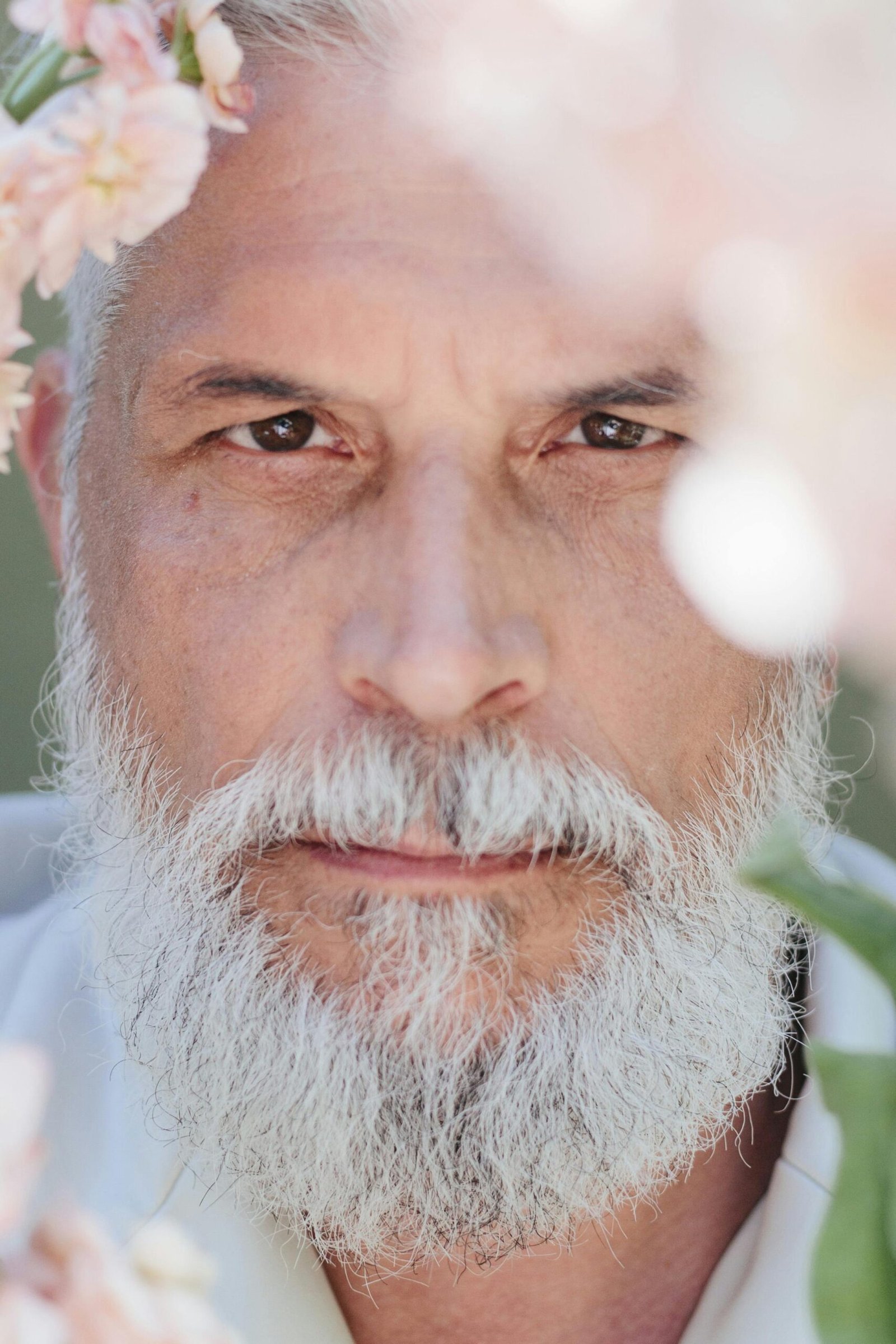 Close-up of an older man surrounded by flowers, reflecting quietly and emotionally