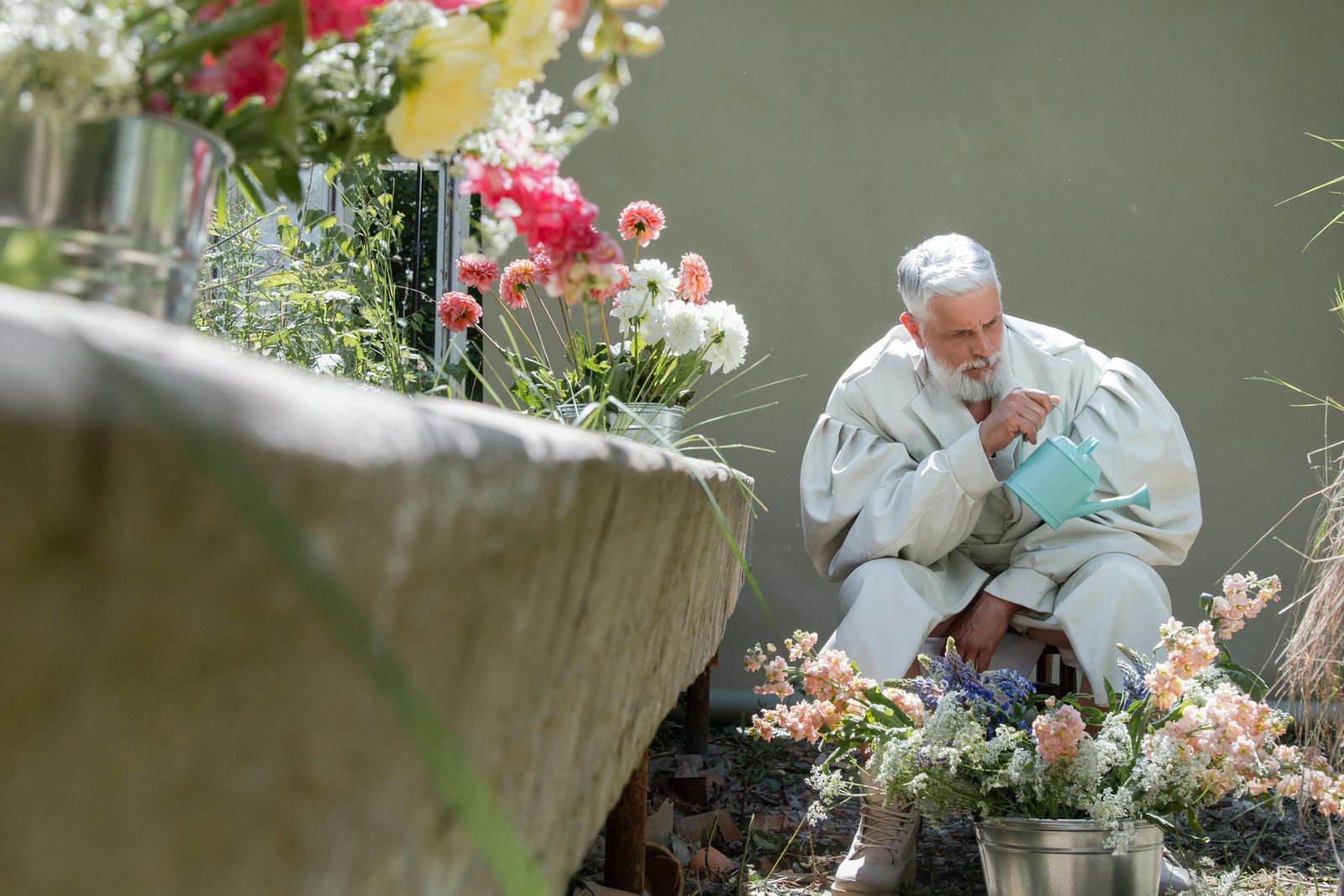 Older man sitting in a garden with flowers, showing calm reflection and emotional stillness