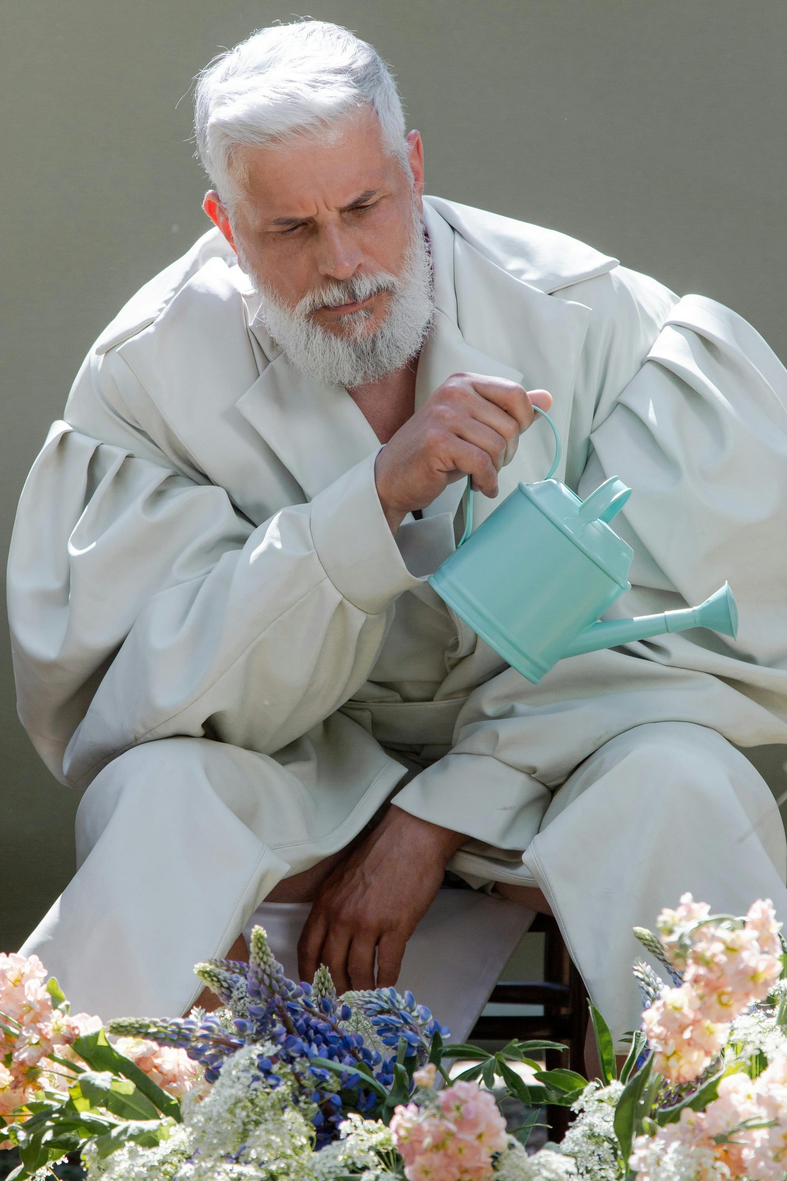Mature man watering flowers, expressing care, patience, and unspoken emotion