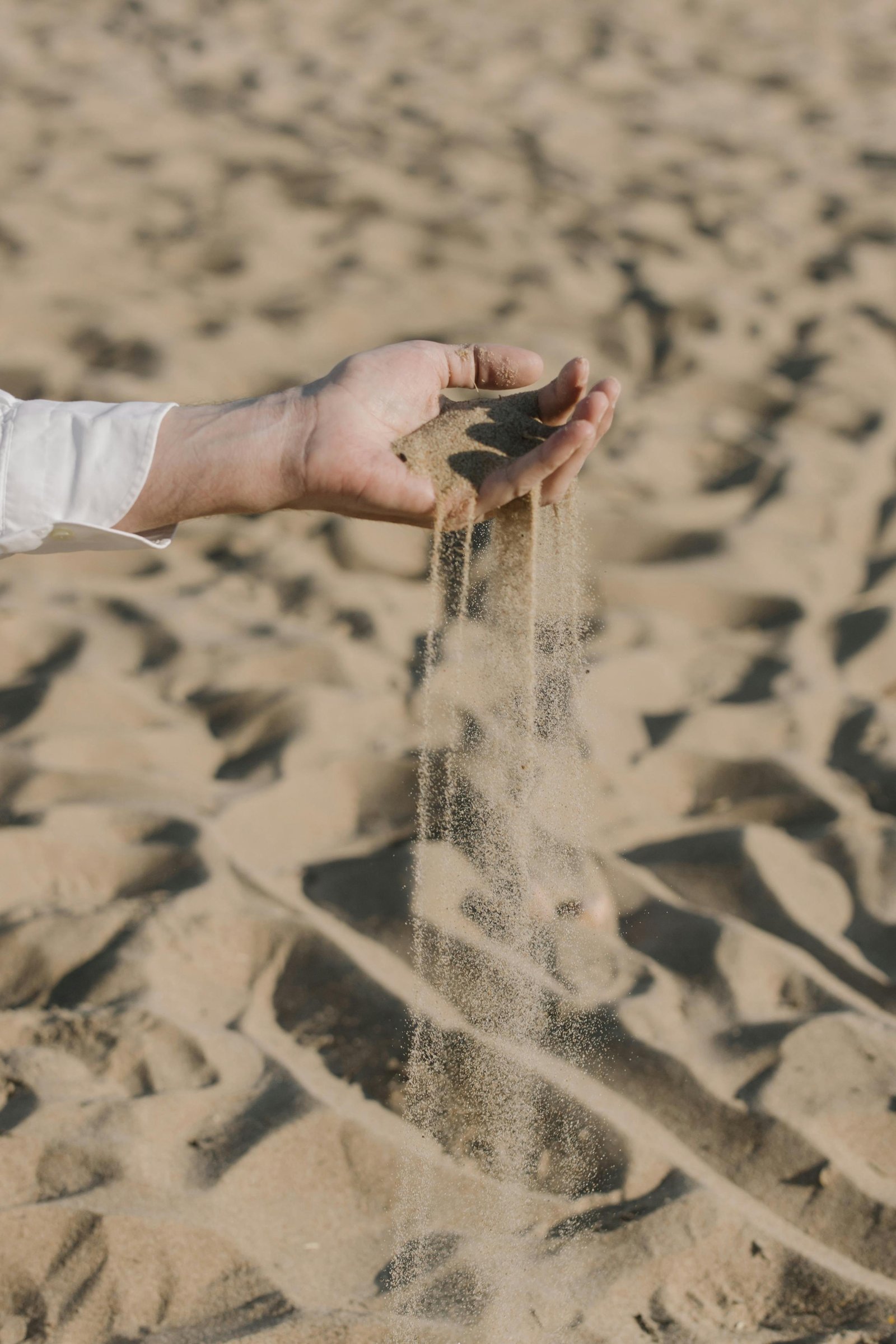 Man holding sand at the beach, representing mindfulness and slowing down through simple hobbies