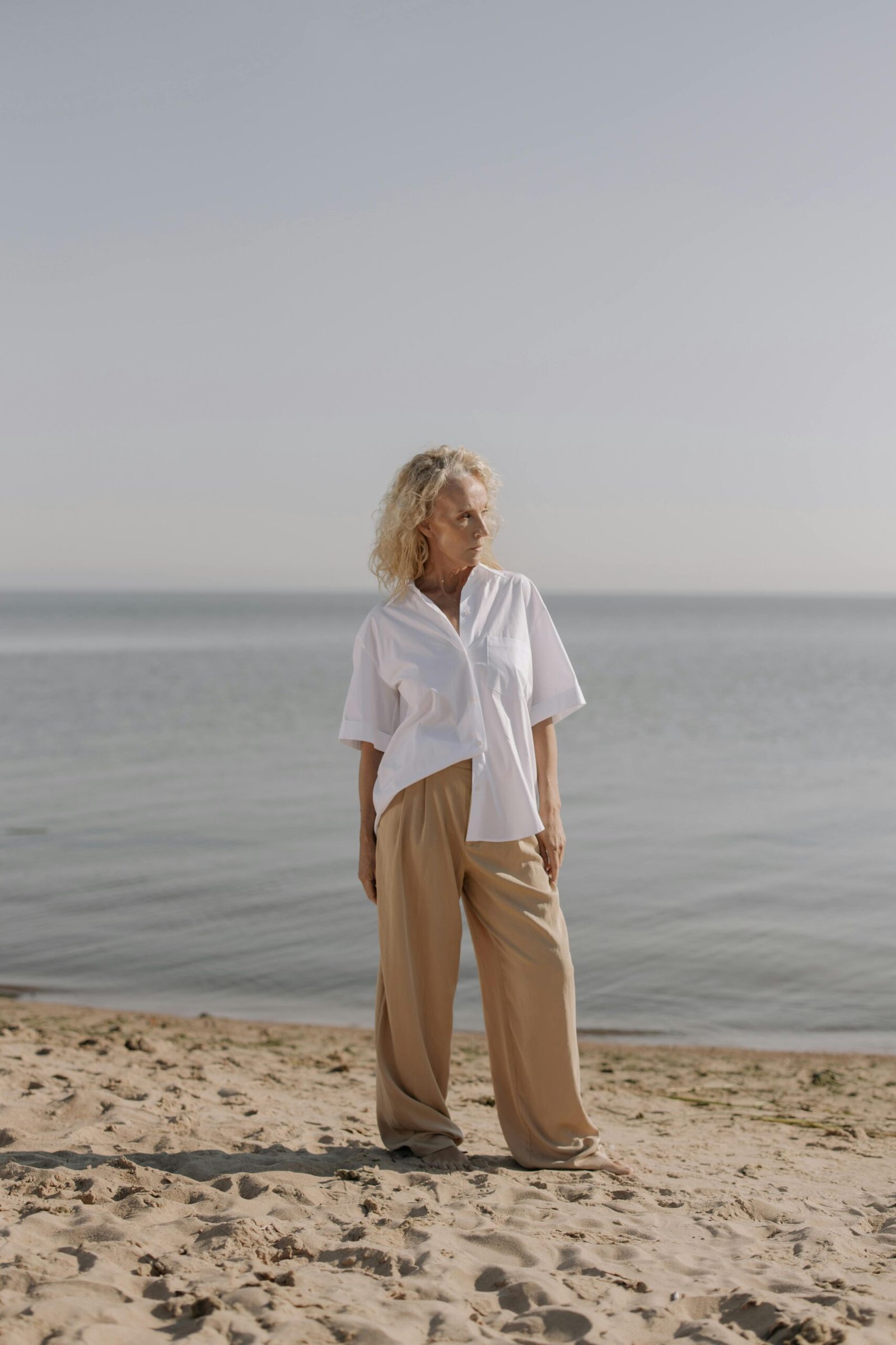 Mature woman by the water, reflecting quietly during a creative second chapter of life