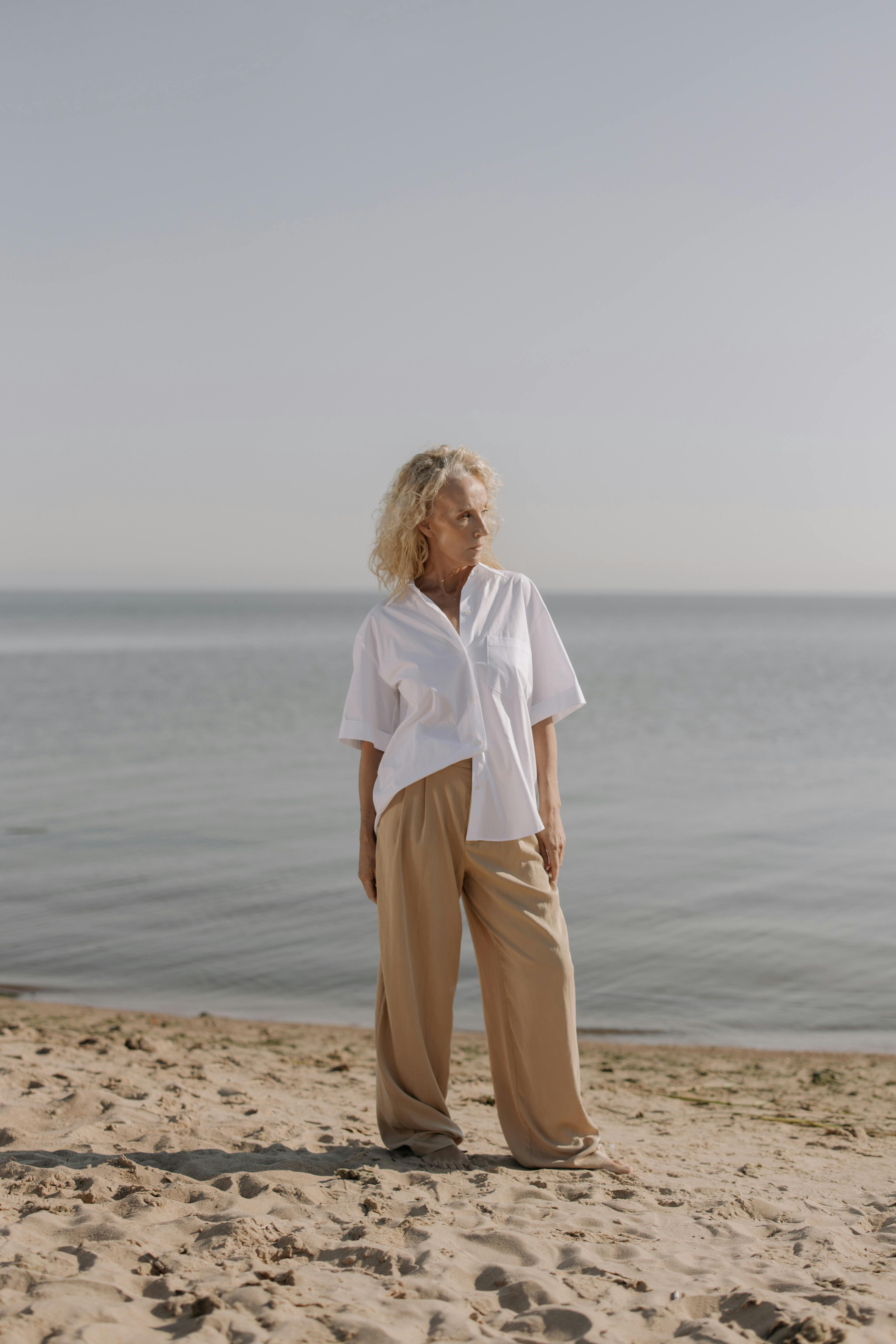 Mature woman by the water, reflecting quietly during a creative second chapter of life