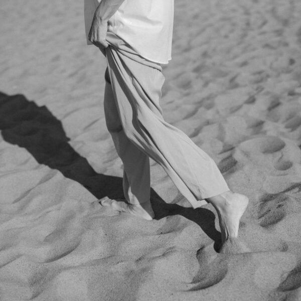 Person walking barefoot on sand, reflecting on movement, pause, and travel