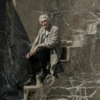 Older man sitting alone on stone steps, quietly reflecting on relationships and life transitions