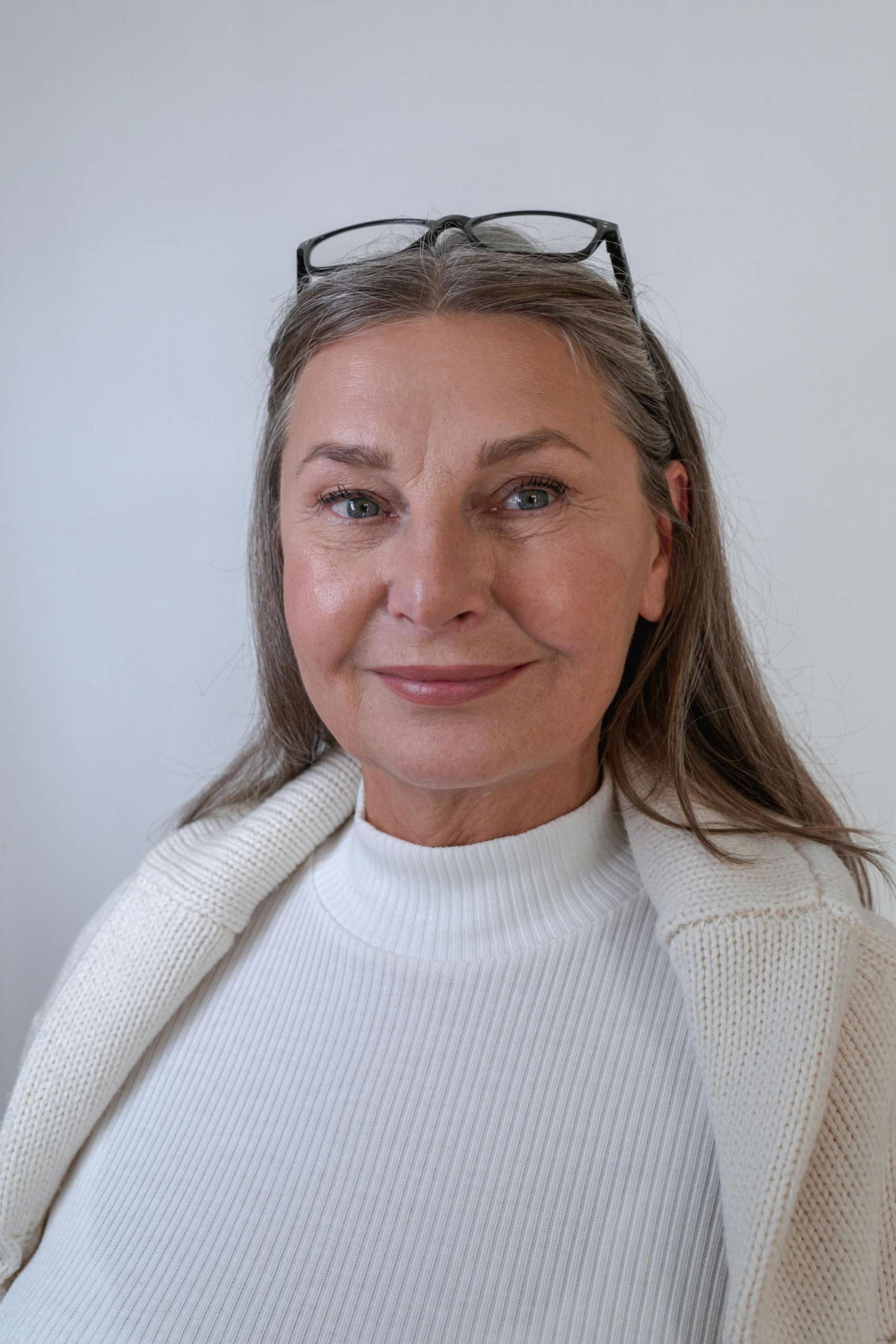 Confident woman over 40 smiling gently in a clean, minimal portrait