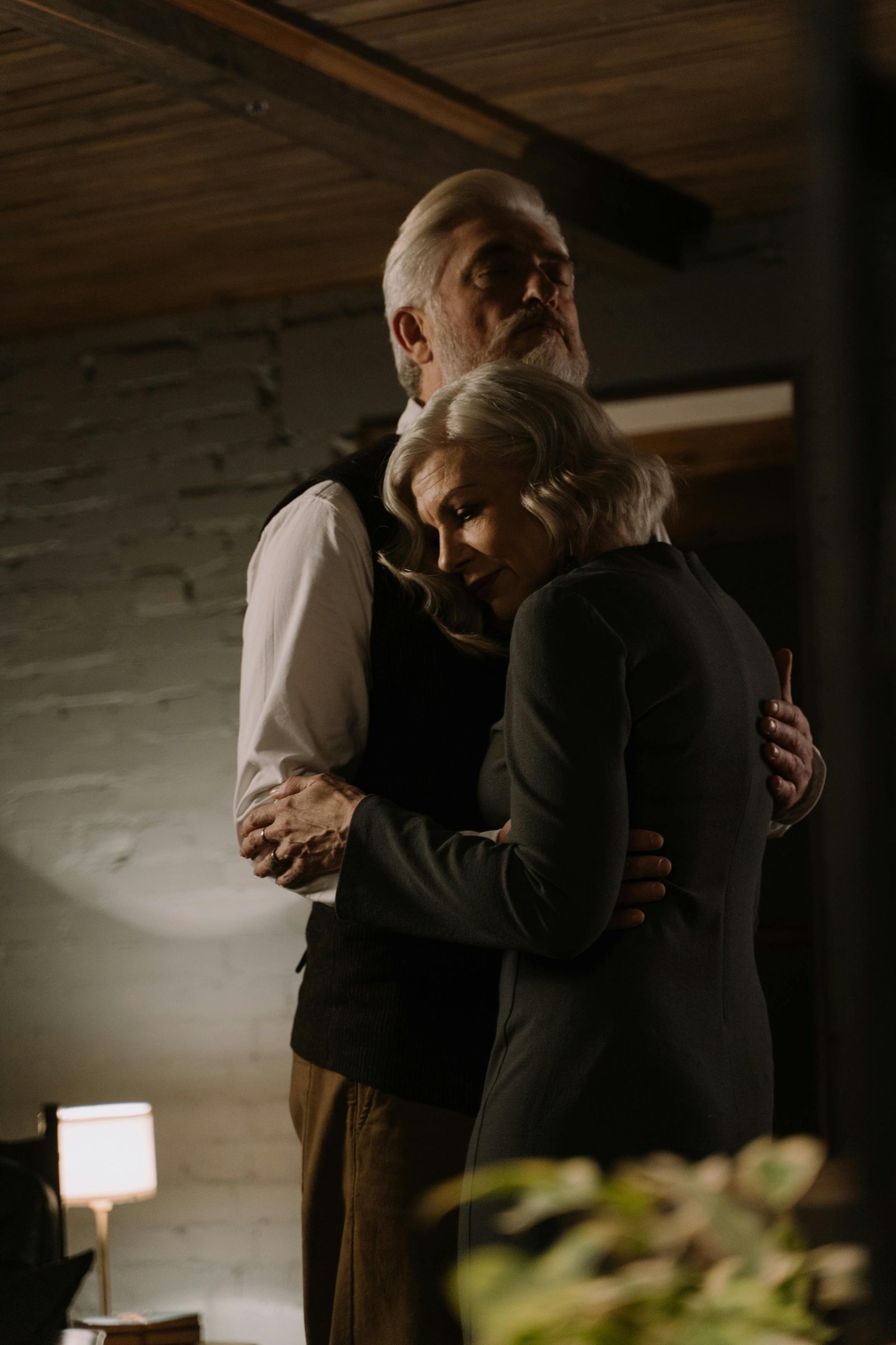 Mature couple standing close together at home, sharing a quiet romantic moment