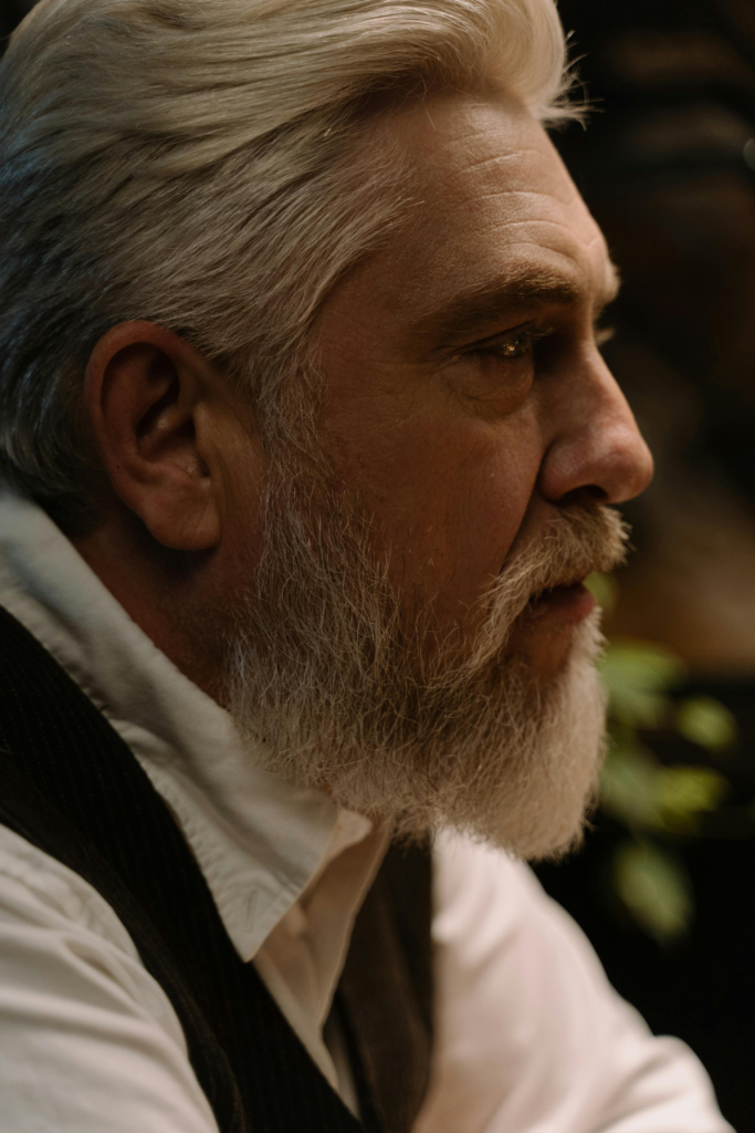 Close-up profile of an older bearded man with a serious, contemplative expression
