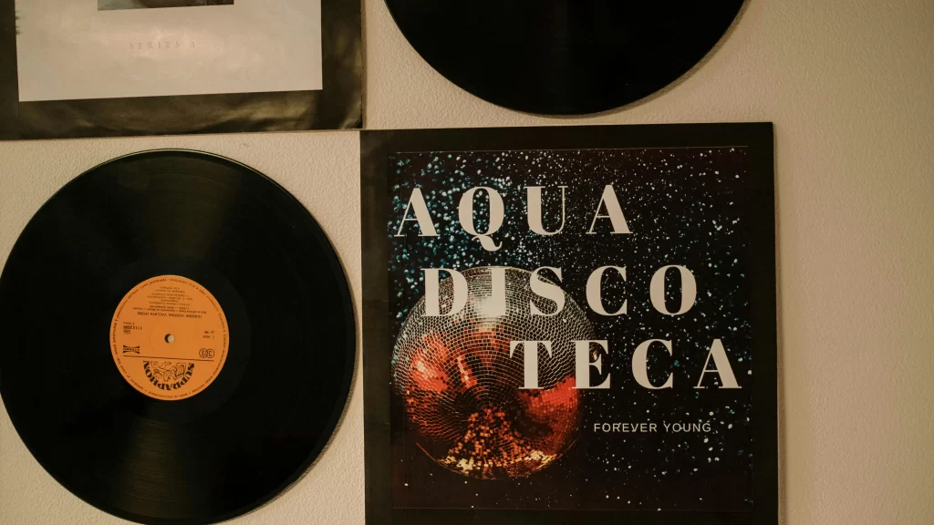 A wall decorated with vinyl records and an album cover titled “Aqua Discoteca Forever Young.”