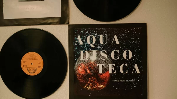 A wall decorated with vinyl records and an album cover titled “Aqua Discoteca Forever Young.”