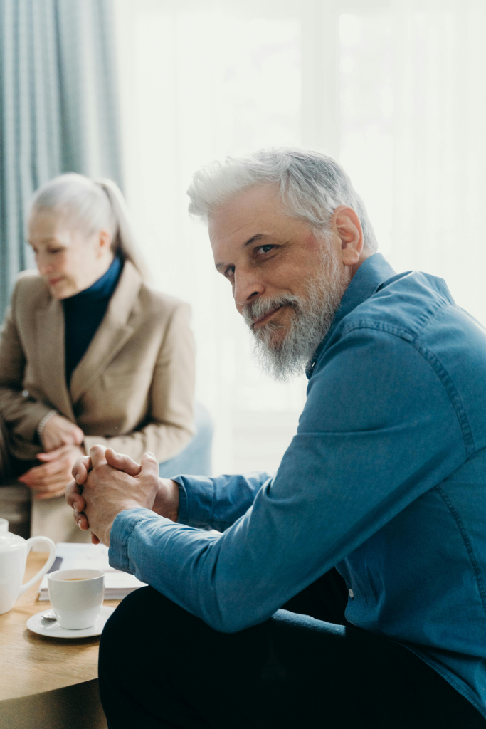 Middle-aged couple sitting together indoors, man looking thoughtful while woman focuses on paperwork