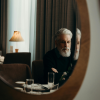 Man in his 50s looking at his reflection, reflecting on body composition changes and muscle loss