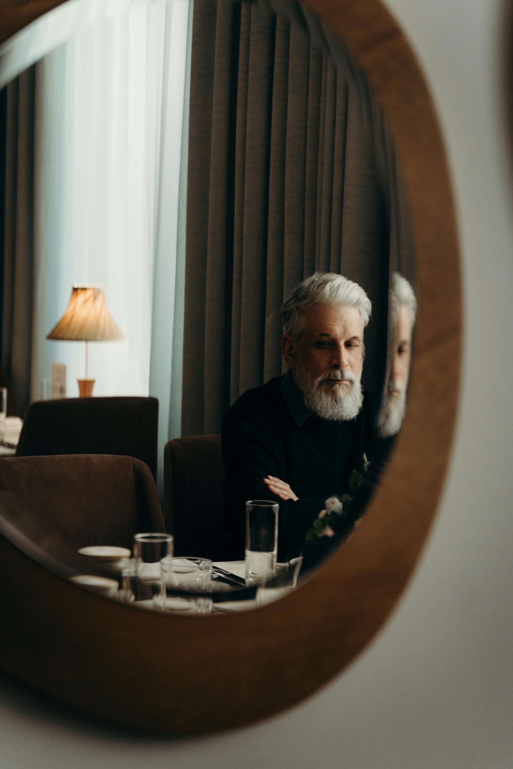 Man in his 50s looking at his reflection, reflecting on body composition changes and muscle loss