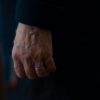 Close-up of an elderly man’s hand with visible veins and a silver wedding ring.