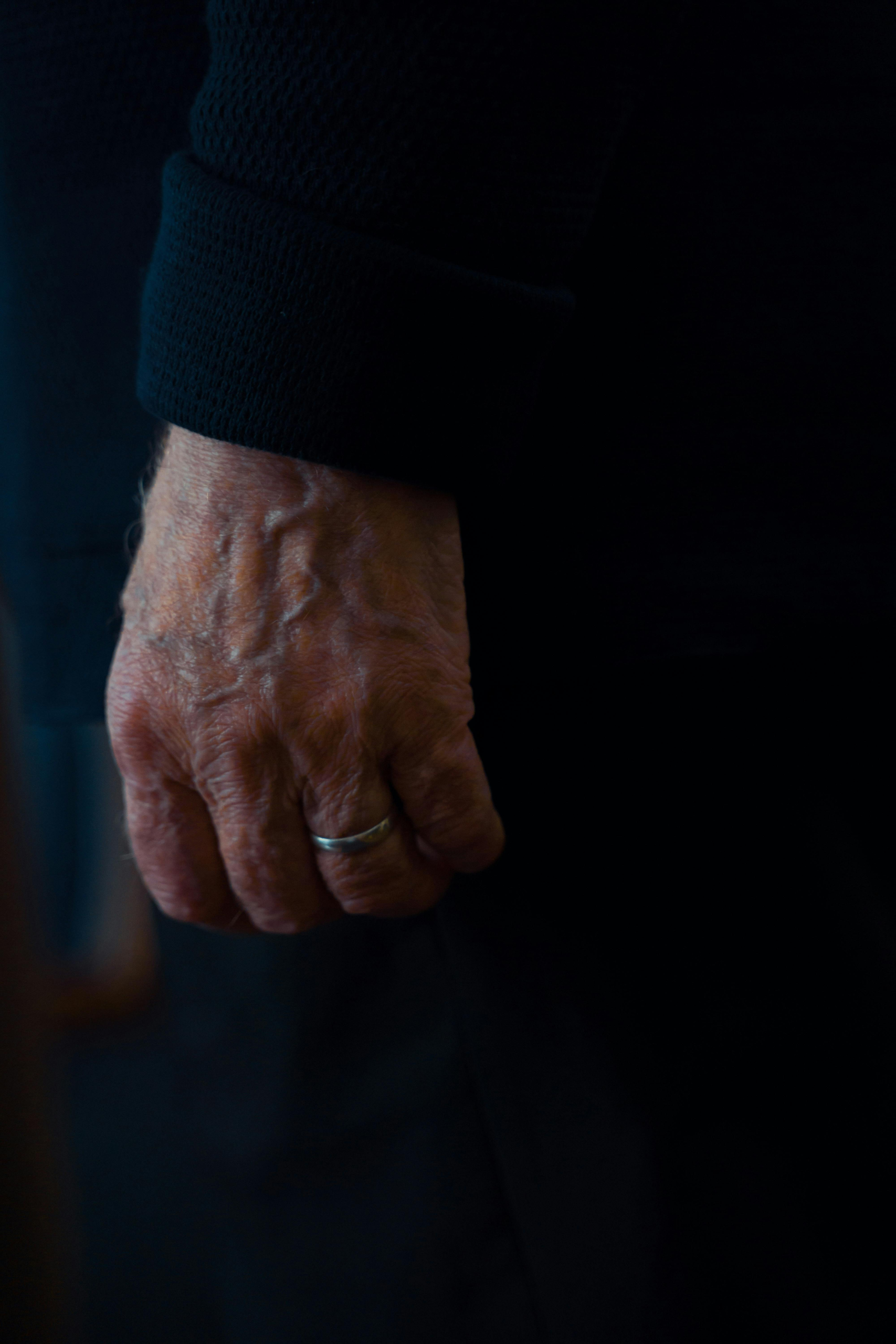 Close-up of an elderly man’s hand with visible veins and a silver wedding ring.