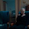 Older woman sitting alone in an armchair, reflecting on future plans in a quiet, dimly lit room
