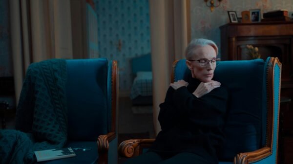 Older woman sitting alone in an armchair, reflecting on future plans in a quiet, dimly lit room