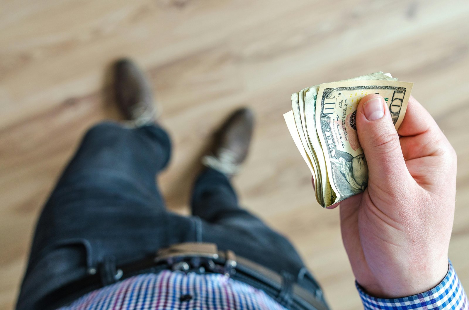 Person holding cash while standing, representing everyday money decisions in midlife