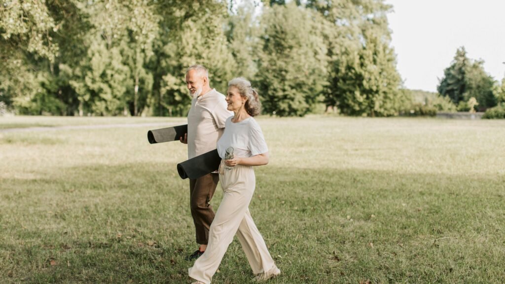 Mature couple walking outdoors carrying yoga mats during a relaxed fitness routine