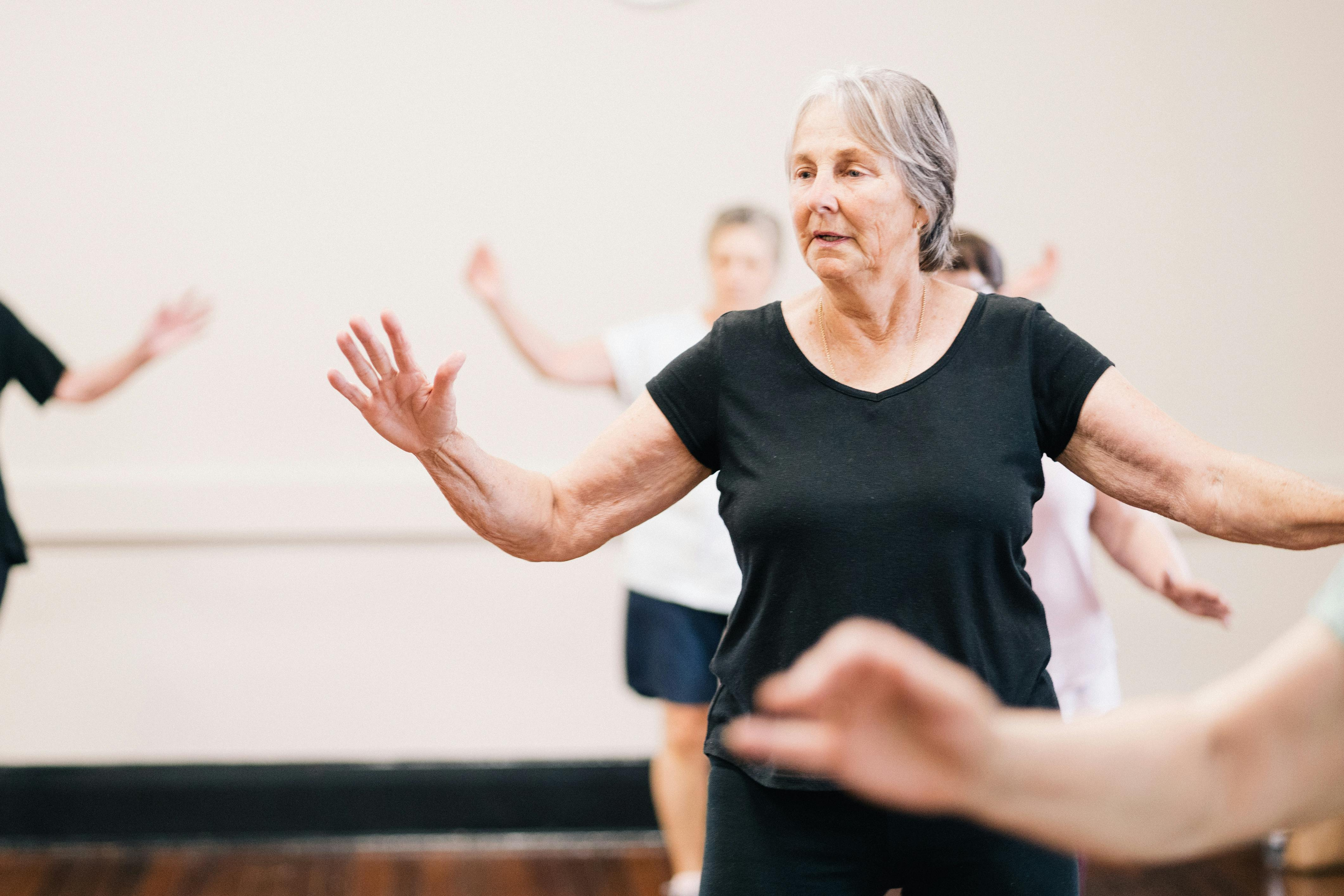 Older woman practicing gentle balance and movement exercises in a group fitness class