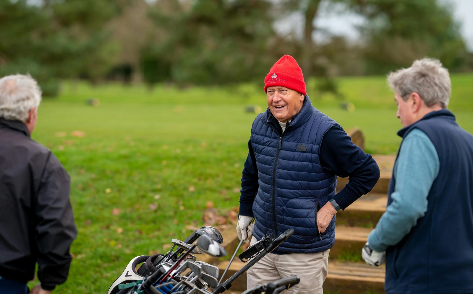 Older men laughing together outdoors during a casual golf outing, valuing connection over performance
