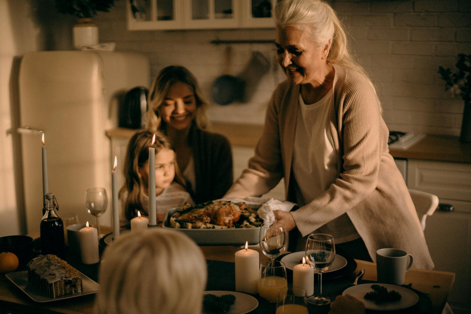 Older woman serving a warm family dinner by candlelight, sharing a quiet moment with loved ones at home