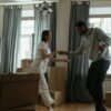 Couple dancing together in a new home surrounded by moving boxes, sharing a light and intimate moment during a life transition