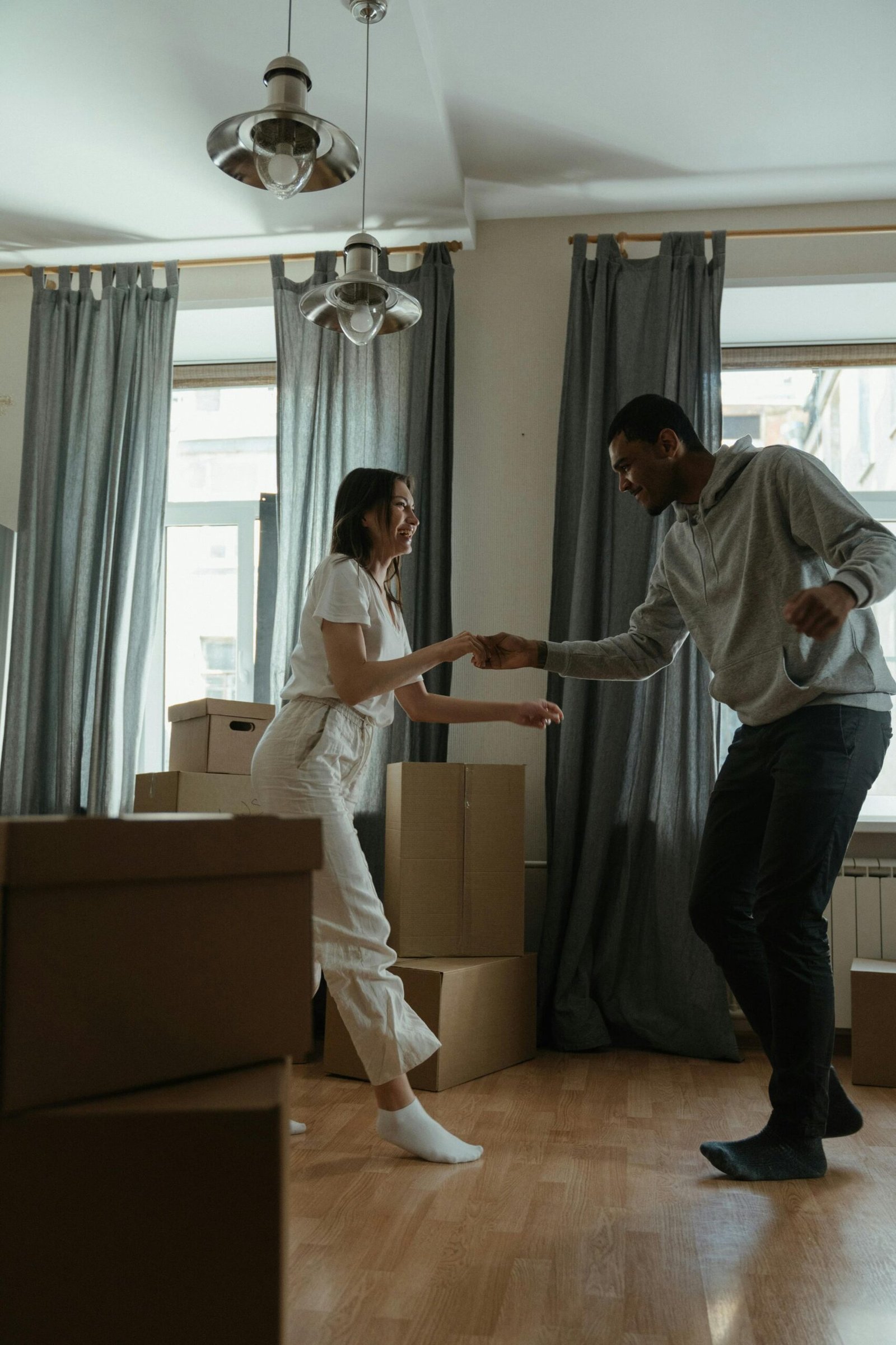 Couple dancing together in a new home surrounded by moving boxes, sharing a light and intimate moment during a life transition