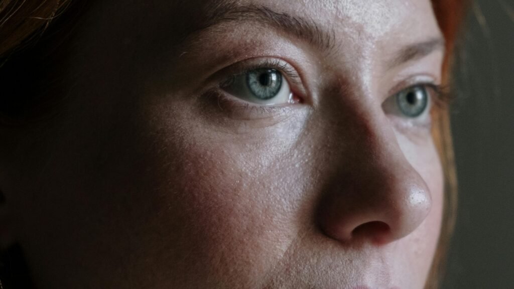 Woman in her 50s with red hair gazing thoughtfully, representing quiet confidence and inner strength