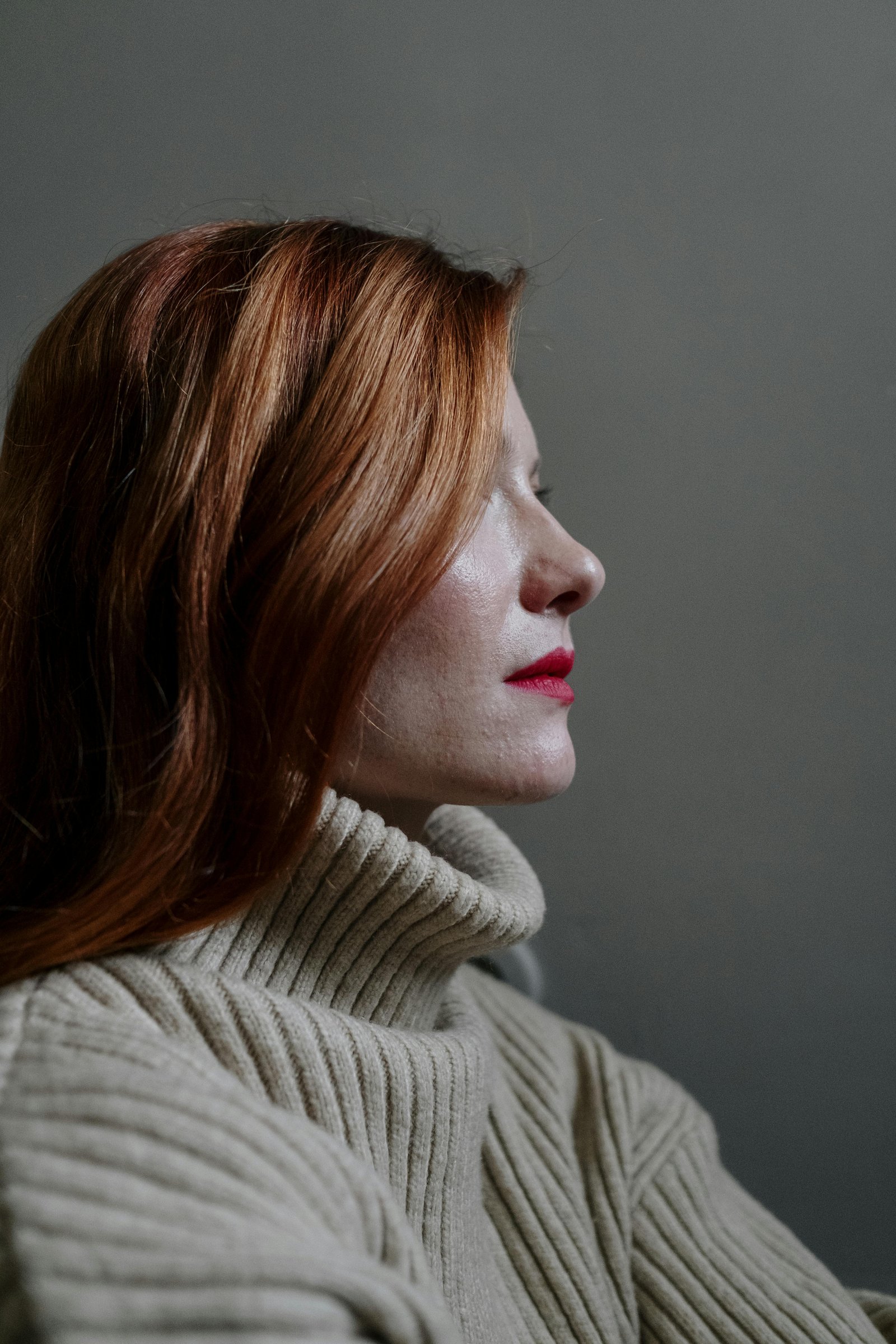 Profile of a mature woman with red hair reflecting calm self-assurance and emotional clarity