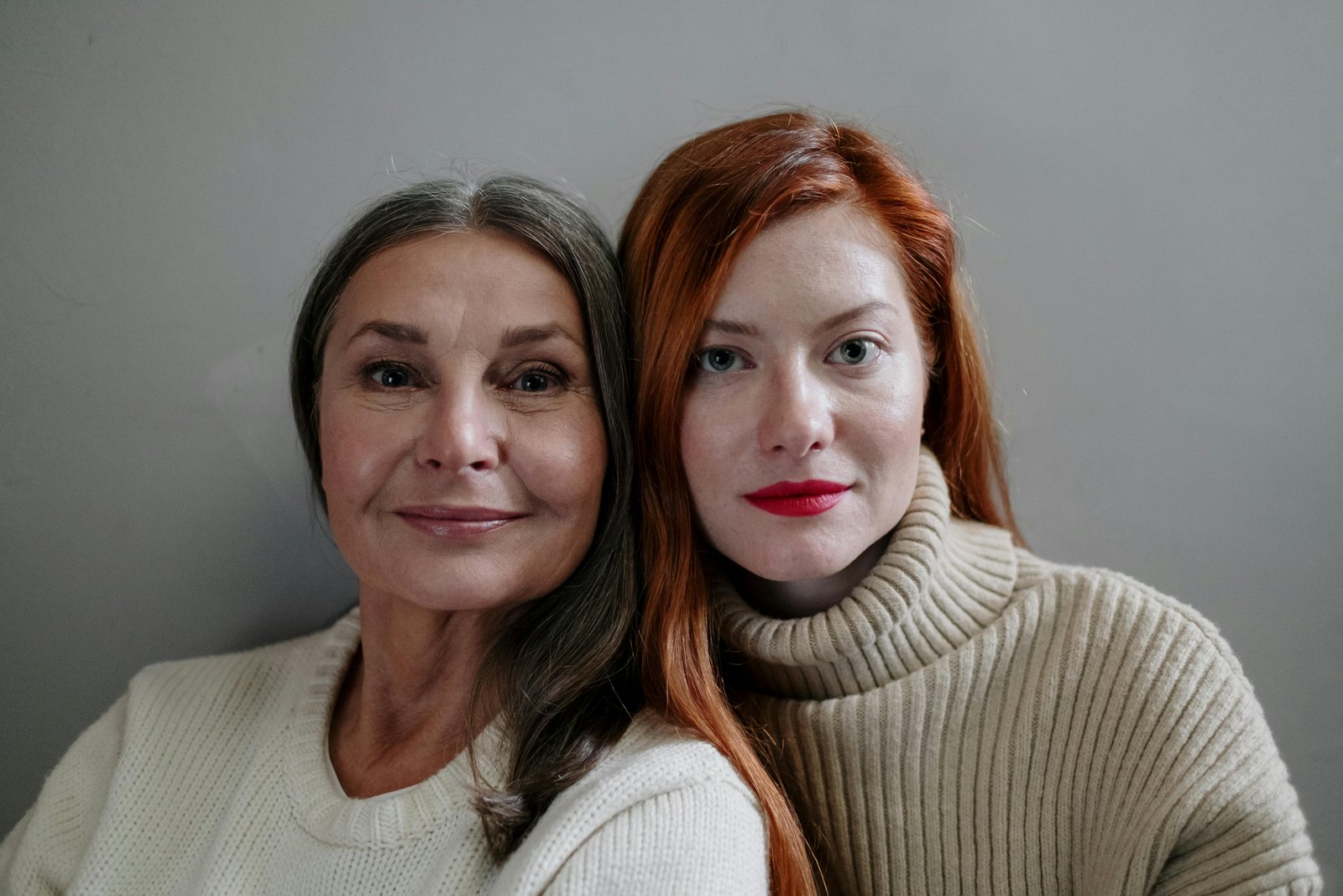 Close-up of two women standing back to back, highlighting contrast in hair color and shared closeness